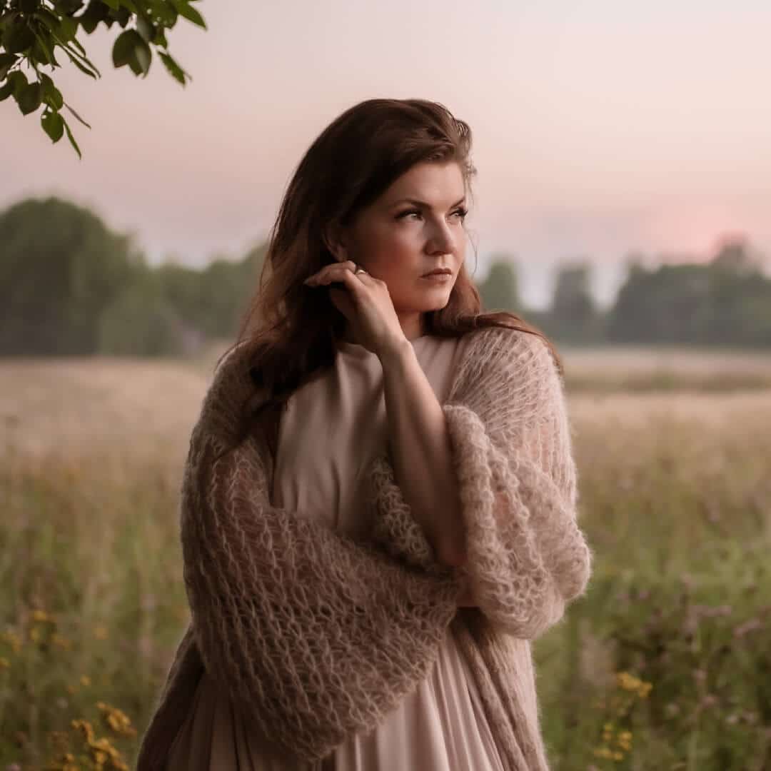 Artisti SUvi Teräsniska katsoo etuviistoon kauniissa suomalaisessa peltomaisemassa