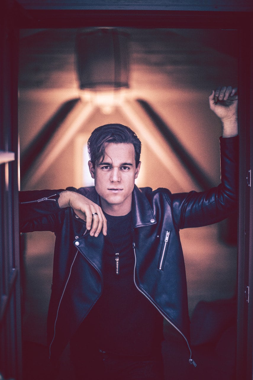 Artisti Mikko Harju nahkatakki päällä nojaa ovenpieleen